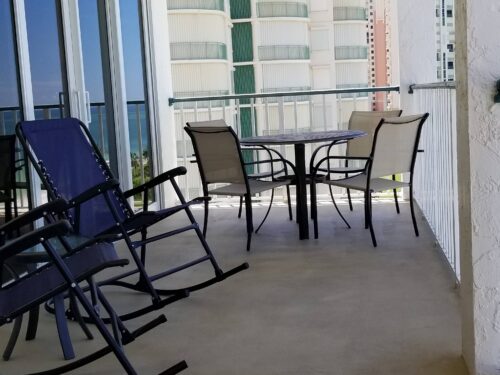 Outdoor balcony dining area at Marco Apollo 1001 with a view of the turquoise sea, ideal for enjoying meals in the ocean air.