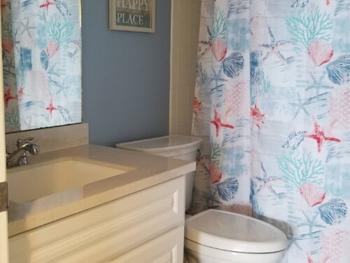 Charming bathroom with a nautical theme, featuring seashell-patterned shower curtains and a serene blue color scheme at Marco Apollo 1001.