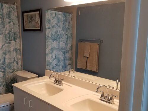 Elegant bathroom with a dual sink vanity, large mirror, and tropical-themed shower curtain in the Marco Apollo 1001 condo.