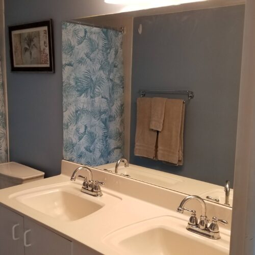 Elegant bathroom with a dual sink vanity, large mirror, and tropical-themed shower curtain in the Marco Apollo 1001 condo.