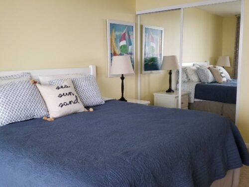 Cozy bedroom with a TV and access to a scenic ocean view balcony at the Marco Apollo 1001 beachfront condo.